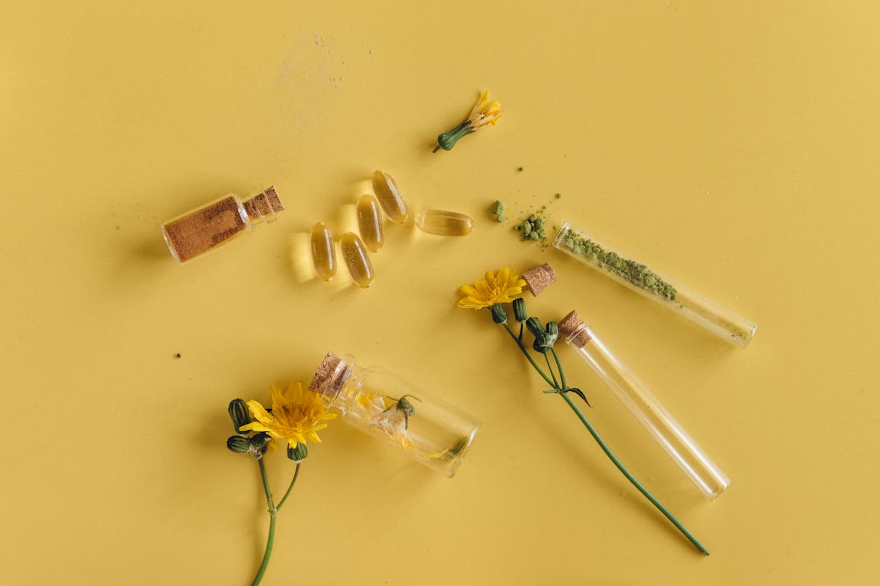 A still life image of herbal medicines and yellow flowers on a yellow background.