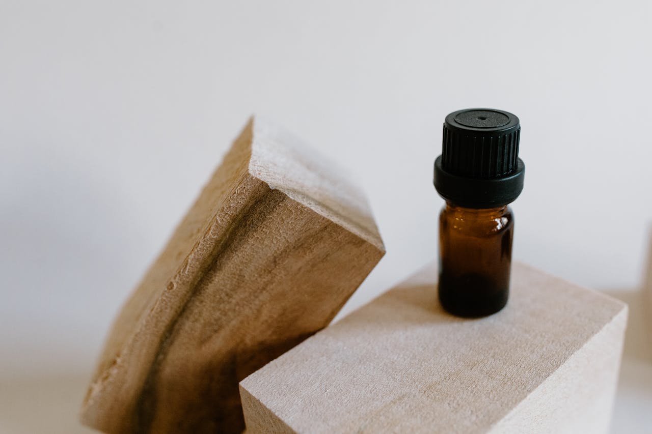 Close-up of an essential oil bottle placed on textured wooden blocks, highlighting a natural and earthy setup.