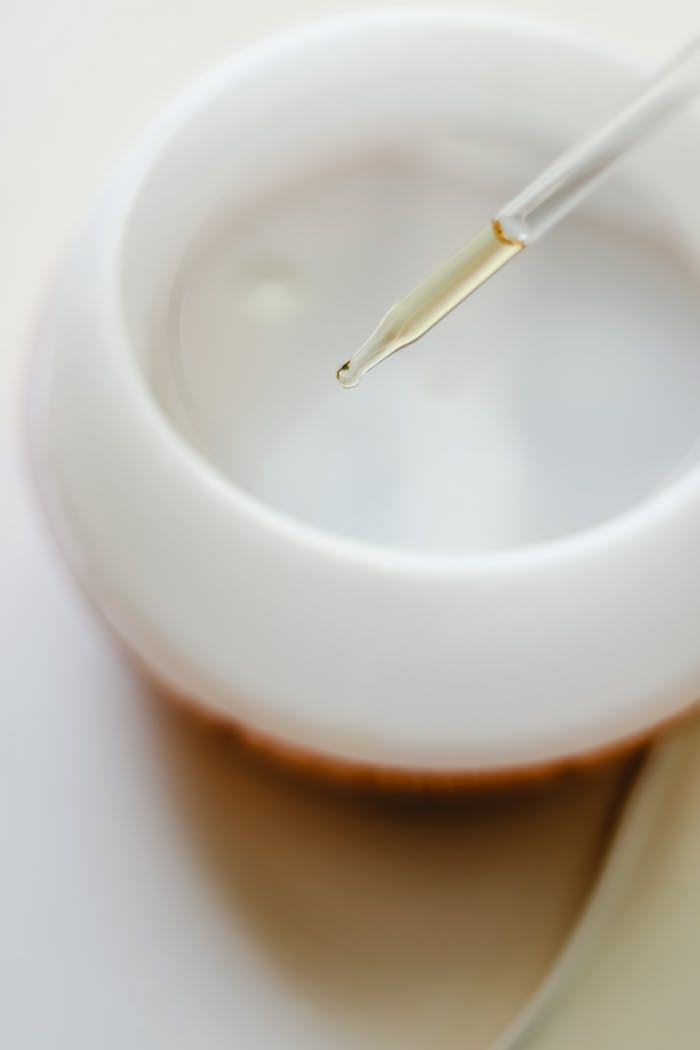 Close-up image of a pipette dispensing essential oil into a white bowl, ideal for aromatherapy themes.