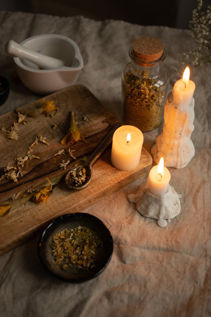 Warm ambiance with candles, dried herbs, and mortar on rustic surface.